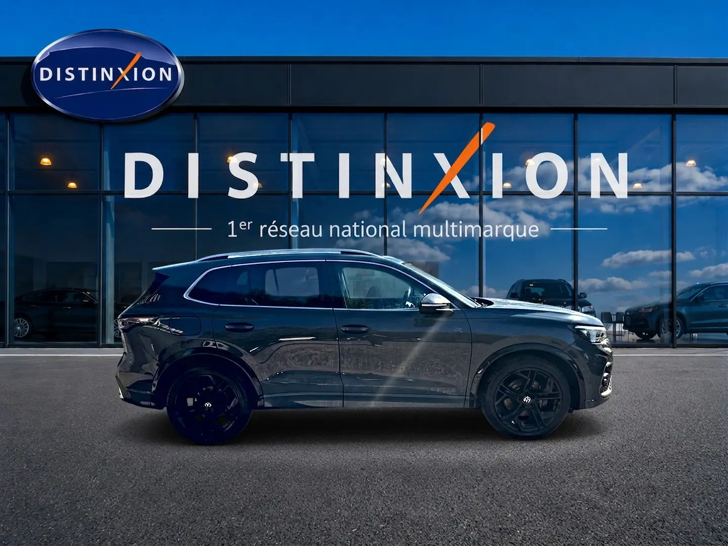 Volkswagen Tiguan 2.0 TDI 150 R-Line gris dauphin vu de profil côté gauche devant une vitrine Distinxion.