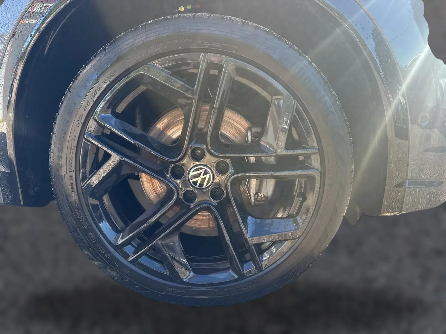 Gros plan sur la jante alu noire brillante avec logo Volkswagen d’un Volkswagen Tiguan gris dauphin.
