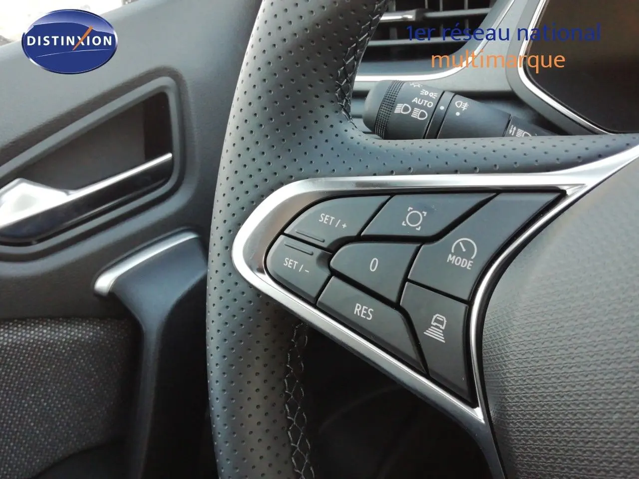 Gros plan sur les commandes à gauche du volant perforé d’un Renault Captur noir étoile métal, intérieur gris-noir.