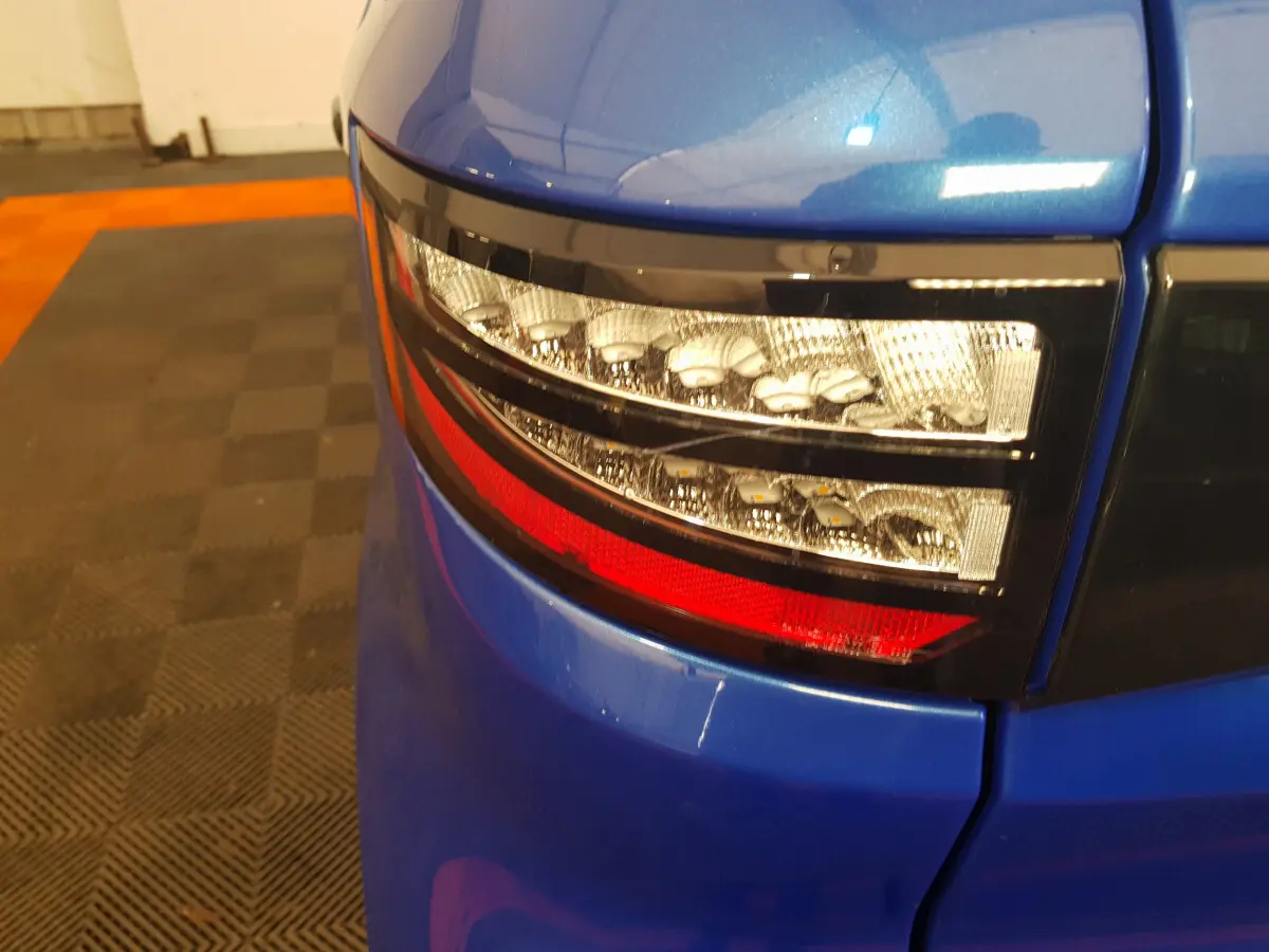 Gros plan sur le feu arrière droit bleu d'une Aixam Ambition 0.5 City Sport 2026 avec finition brillante.