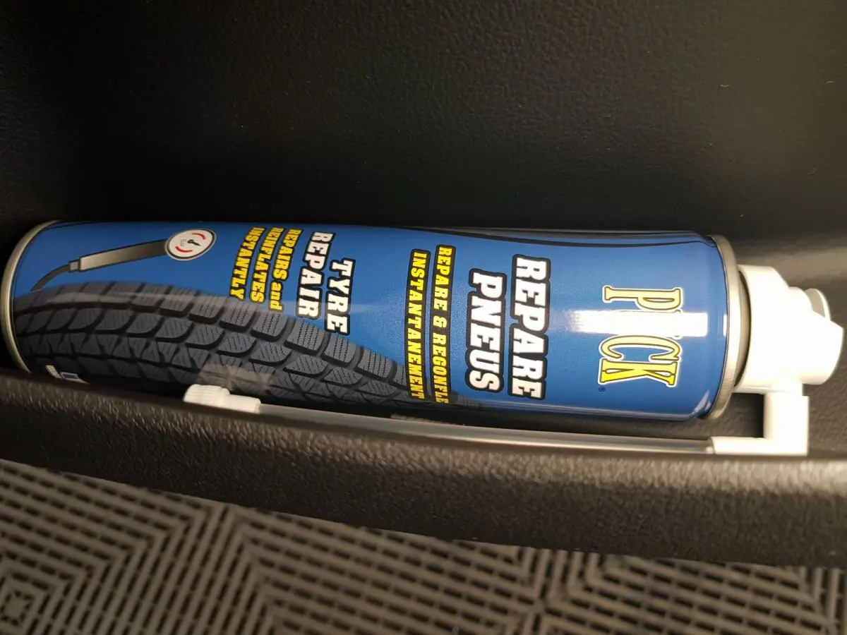 Image ne montrant pas le véhicule AIXAM AMBITION 0.5 CITY SPORT bleu, mais un produit de réparation pneus dans un rangement intérieur.