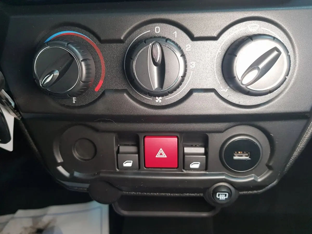 Gros plan sur la console centrale de l'AIXAM AMBITION 0.5 CITY SPORT 2026 avec commandes de climatisation et bouton d'alerte rouge.