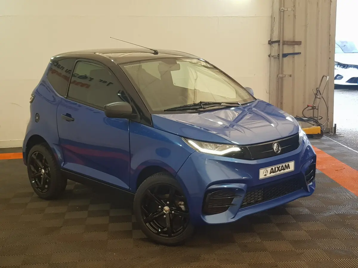 Vue 3/4 avant d'une Aixam Ambition 0.5 City Sport bleu avec jantes noires et rétroviseur caméra côté gauche.