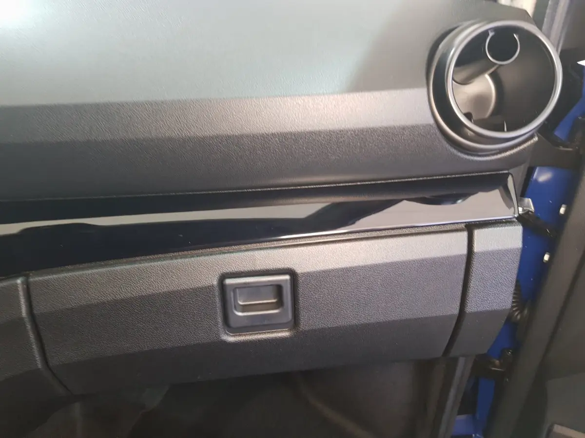 Vue rapprochée de la boîte à gants et de la sortie d'air ronde côté passager d'une Aixam Ambition 0.5 City Sport bleue.