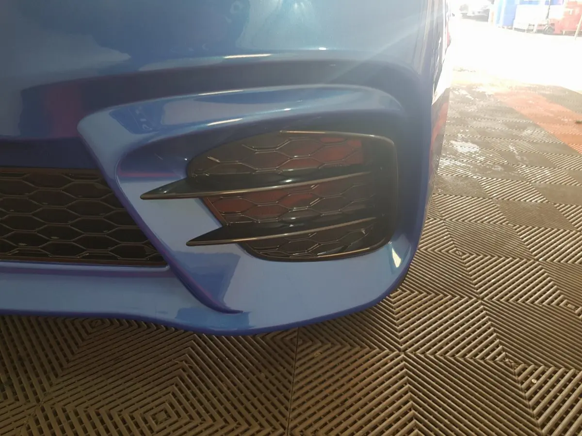 Gros plan sur la partie avant droite bleue de l'AIXAM AMBITION 0.5 CITY SPORT avec grille noire et détails aérés.