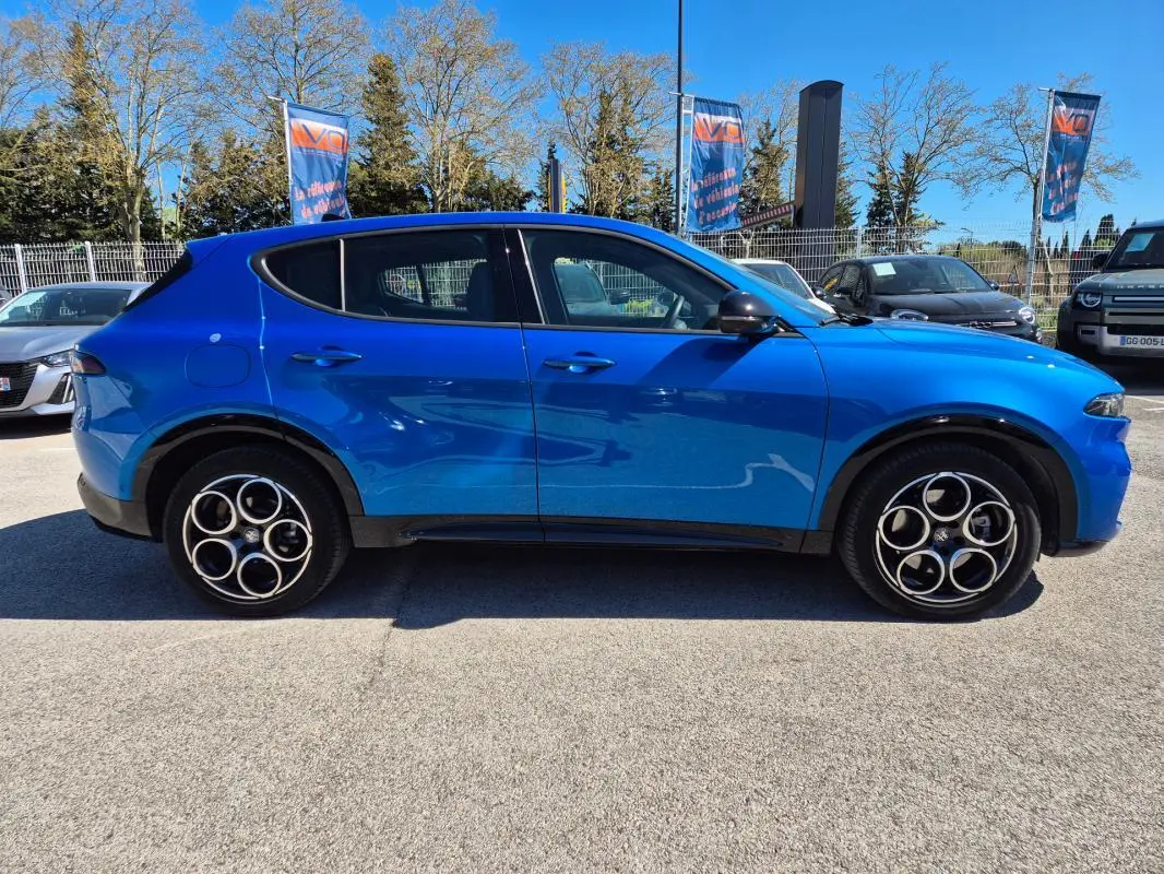 Vue de profil côté gauche d'un Alfa Romeo Tonale bleu 2025 avec jantes alliage distinctives et rétroviseurs noirs.