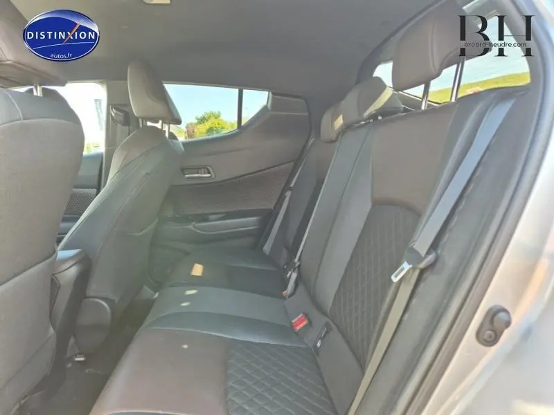 Vue latérale droite de l'intérieur arrière du Toyota C-HR gris aluminium, sièges mi-cuir chocolat avec surpiqûres losanges.