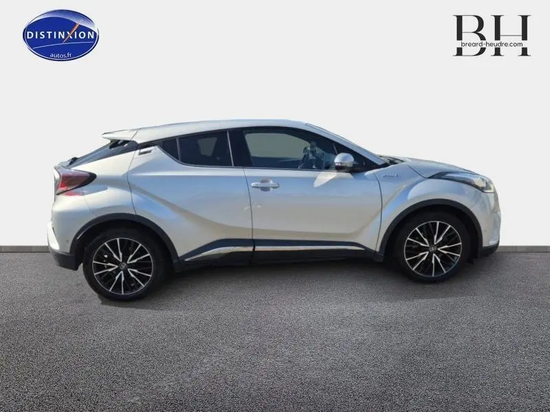 Profil droit du Toyota C-HR 122h Distinctive gris aluminium avec jantes alliage et lignes sculptées visibles