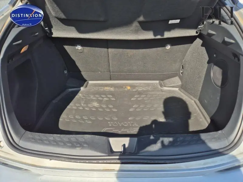 Coffre ouvert d’un Toyota C-HR gris aluminium de 2019, montrant le tapis de coffre avec logo Toyota et intérieur noir.