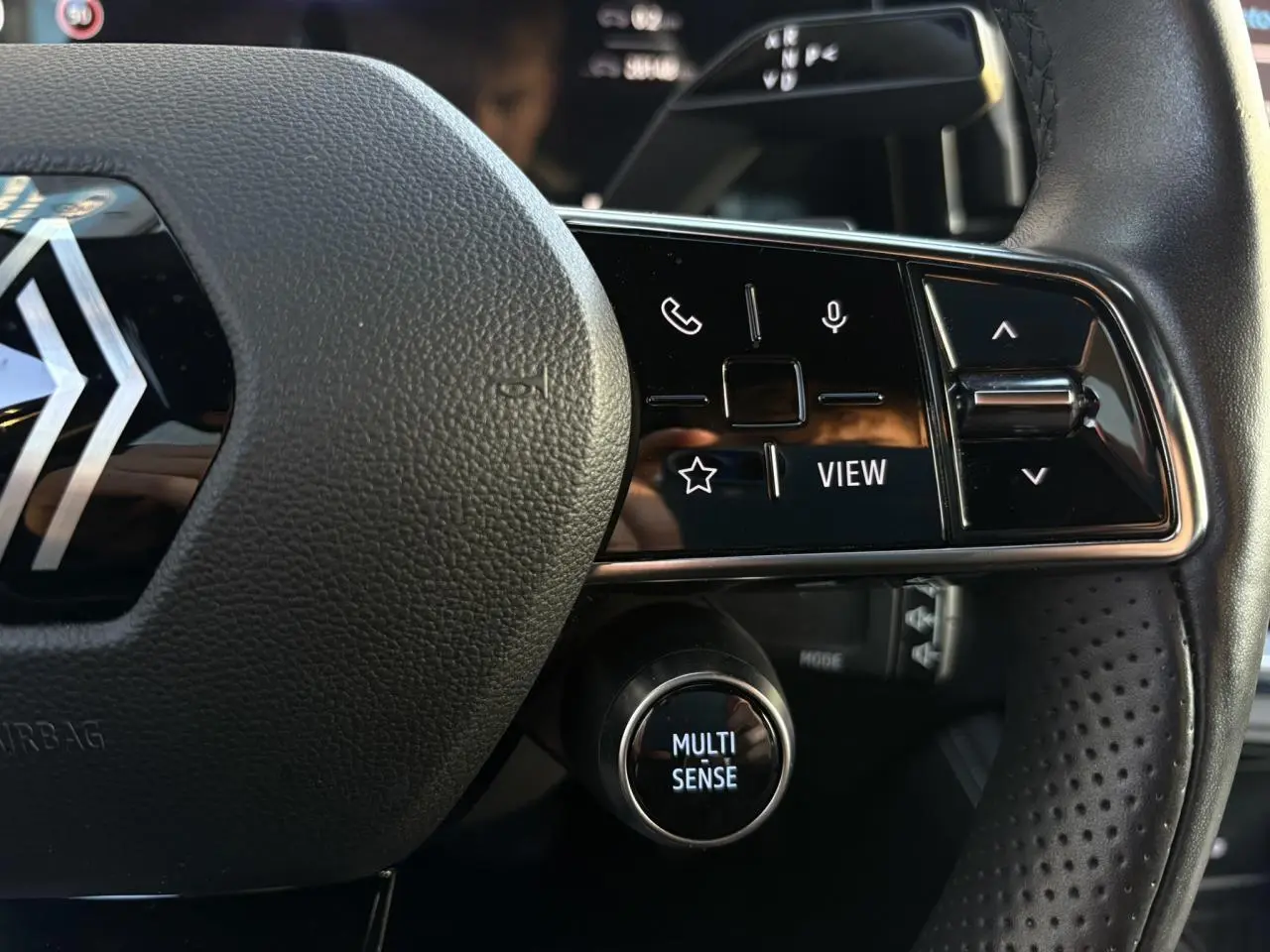 Gros plan sur le volant cuir noir perforé du Renault Austral 2023 avec commandes multifonctions et bouton Multi Sense.