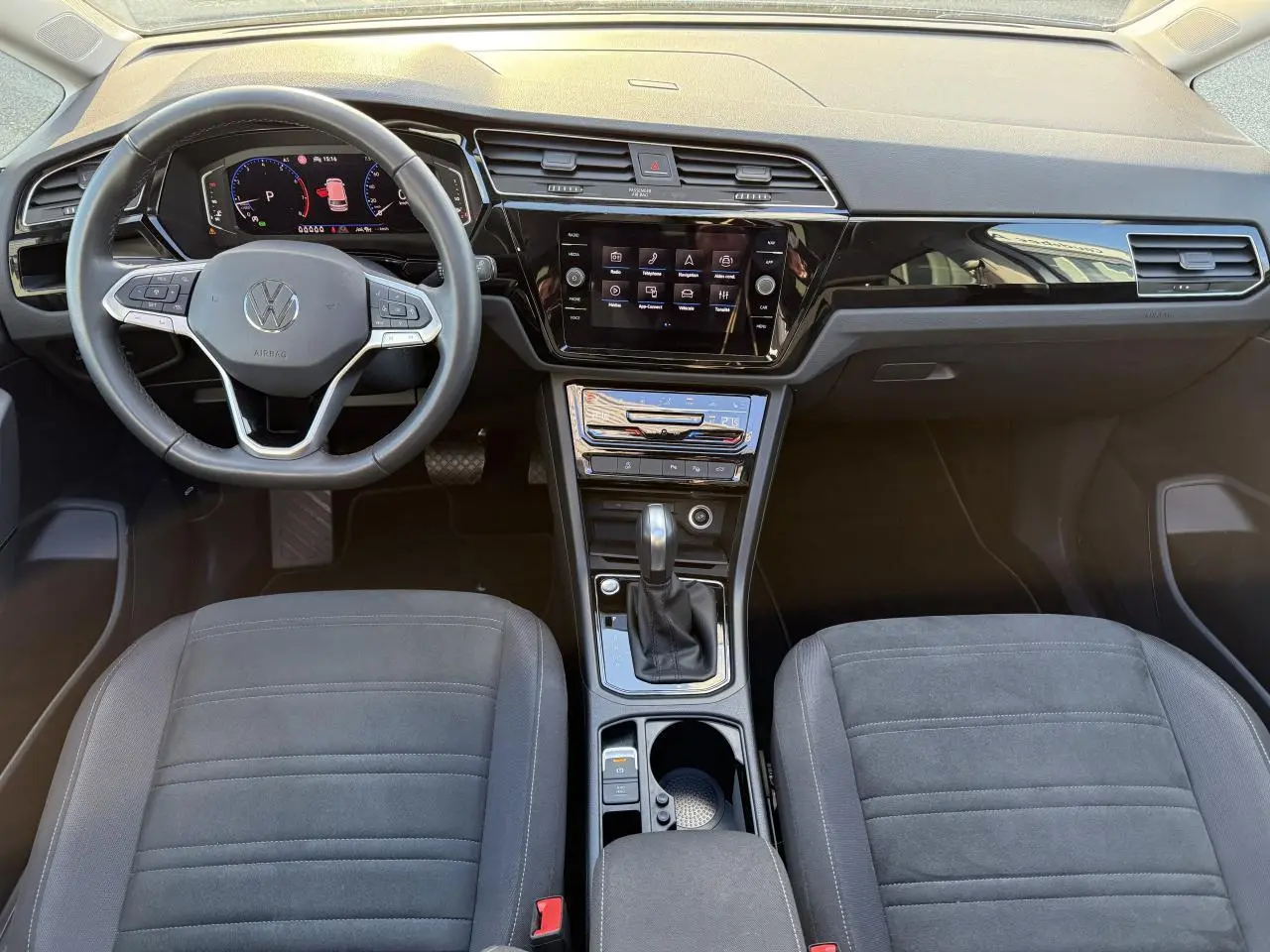 Vue intérieure frontale du tableau de bord et volant cuir multifonction du Volkswagen Touran 2025 en microfleece gris.