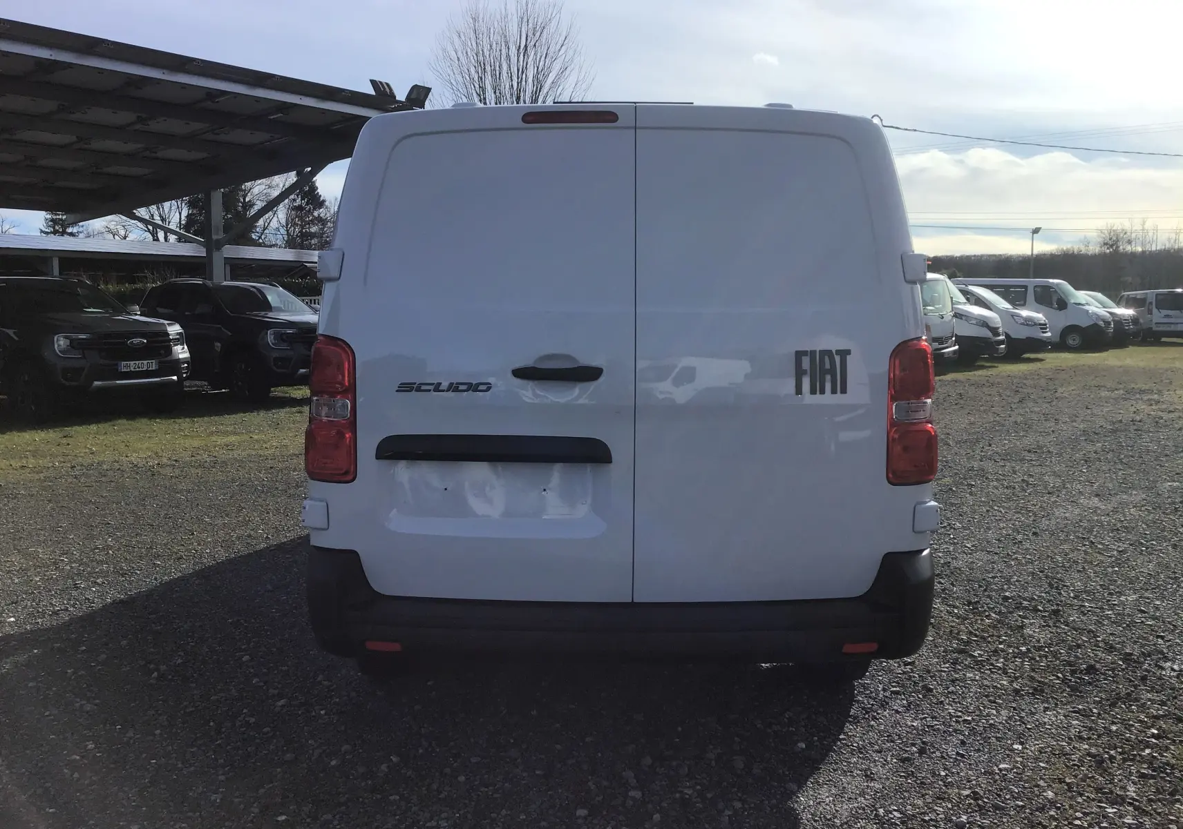 Vue arrière d'un FIAT Scudo Fourgon blanc 2024 avec portes battantes et feux arrière rouges, stationné en extérieur.