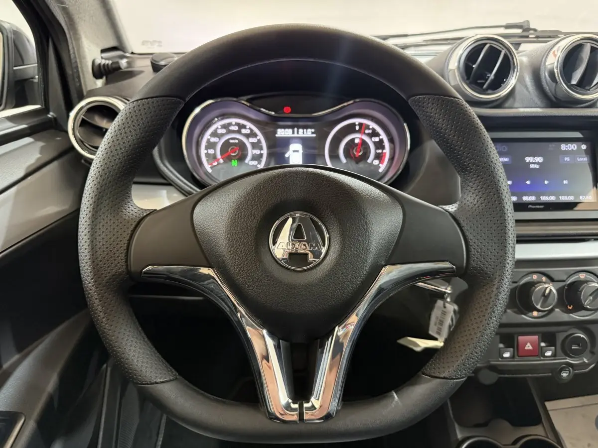 Vue rapprochée du volant noir et perforé de l'AIXAM AMBITION 0.5 CROSSOVER PREMIUM gris foncé, avec tableau de bord et écran central.