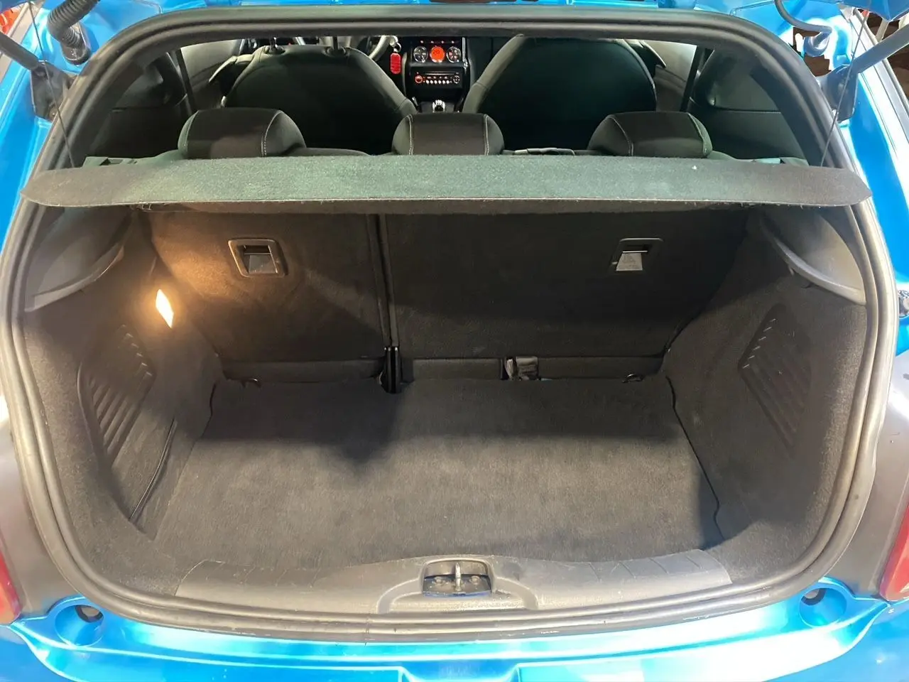 Coffre ouvert vu de l’arrière d’une Citroën DS3 bleu avec toit blanc, montrant l’espace de chargement vide.