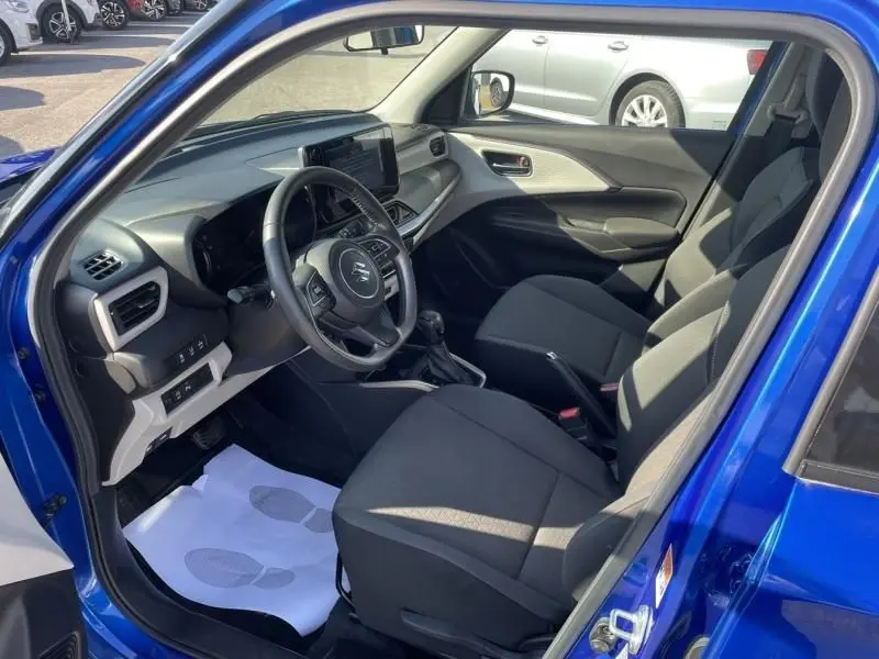 Intérieur de la Suzuki Swift 2024 bleu métal vu côté conducteur, avec tableau de bord moderne et sièges noirs.
