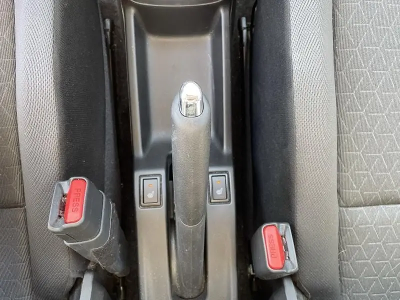 Vue plongeante sur le frein à main et les commandes de sièges chauffants dans l'habitacle d'une Suzuki Swift bleu métal 2024.