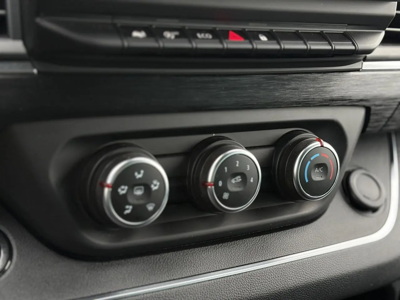 Gros plan sur les commandes de climatisation du tableau de bord du Nissan Primastar Combi noir métal 2025.