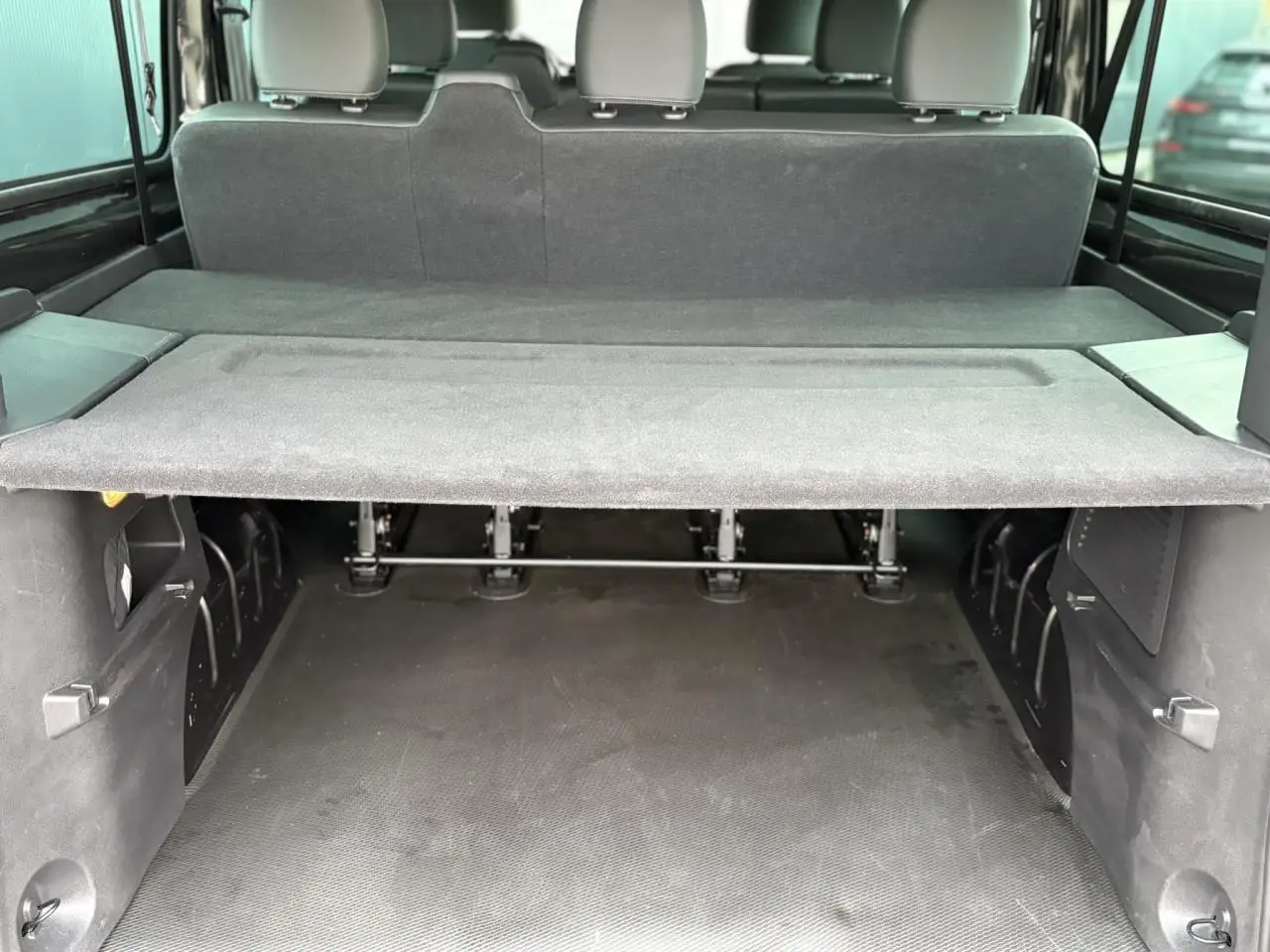 Coffre spacieux vu de l'arrière dans un Nissan Primastar Combi noir métallisé avec banquette arrière et cache-bagages.