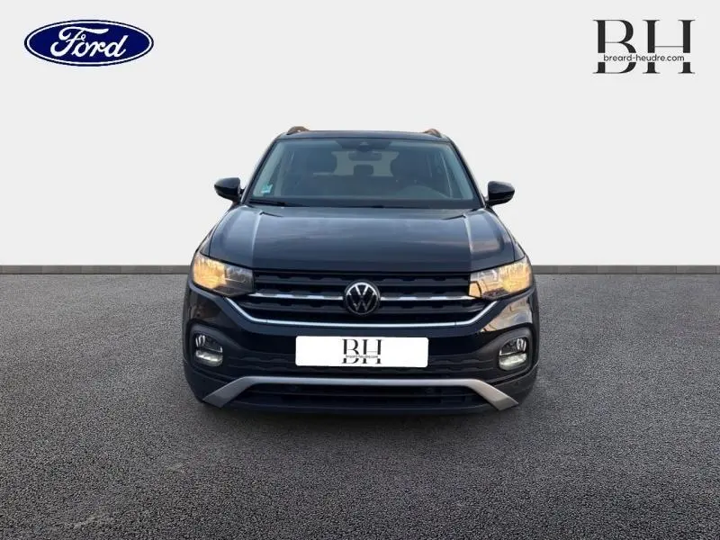 Volkswagen T-Cross noir intense nacré vu de face, avec calandre chromée et phares allumés.