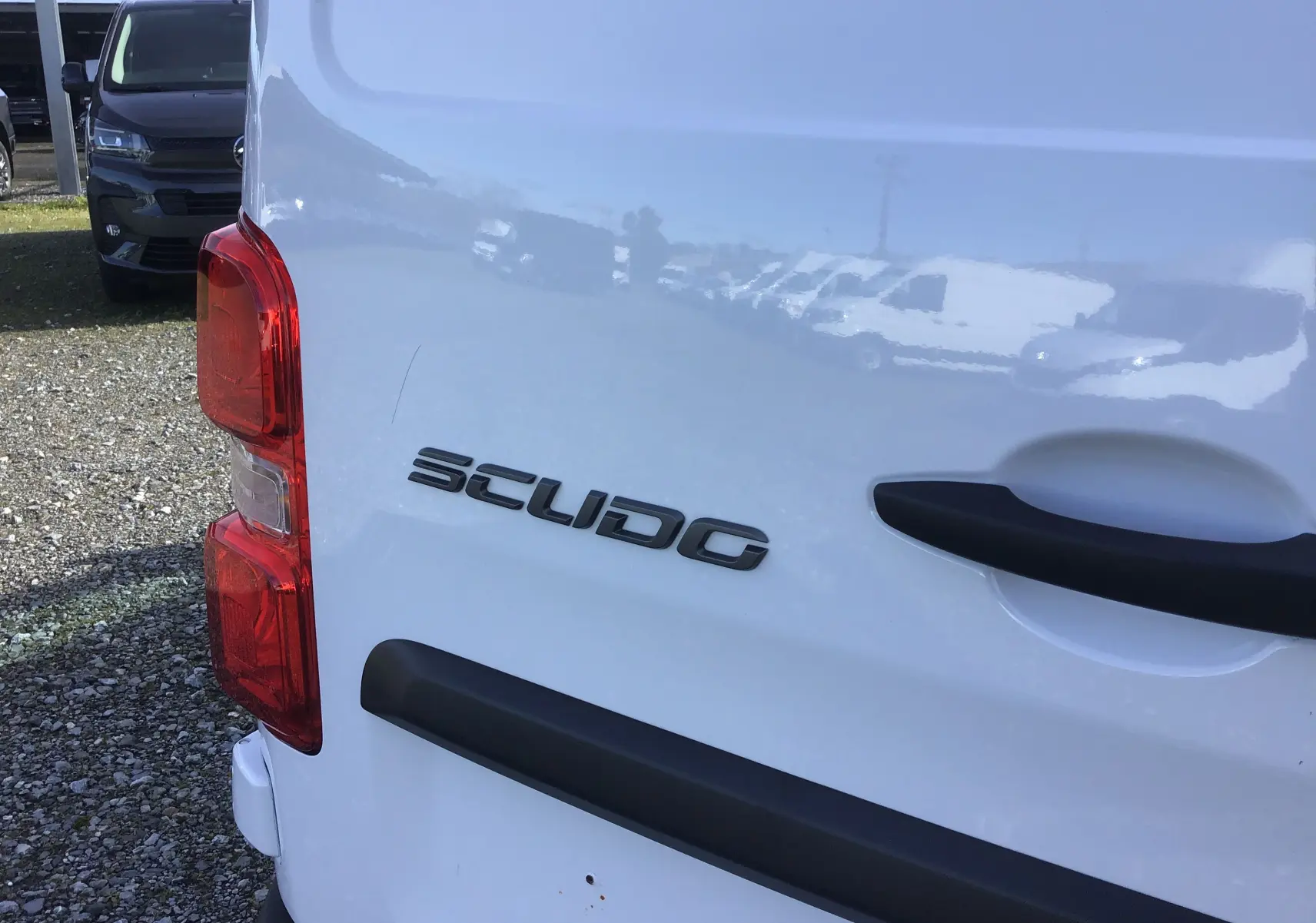 Gros plan sur l’arrière gauche blanc du FIAT Scudo Fourgon avec logo et poignée noire visible.