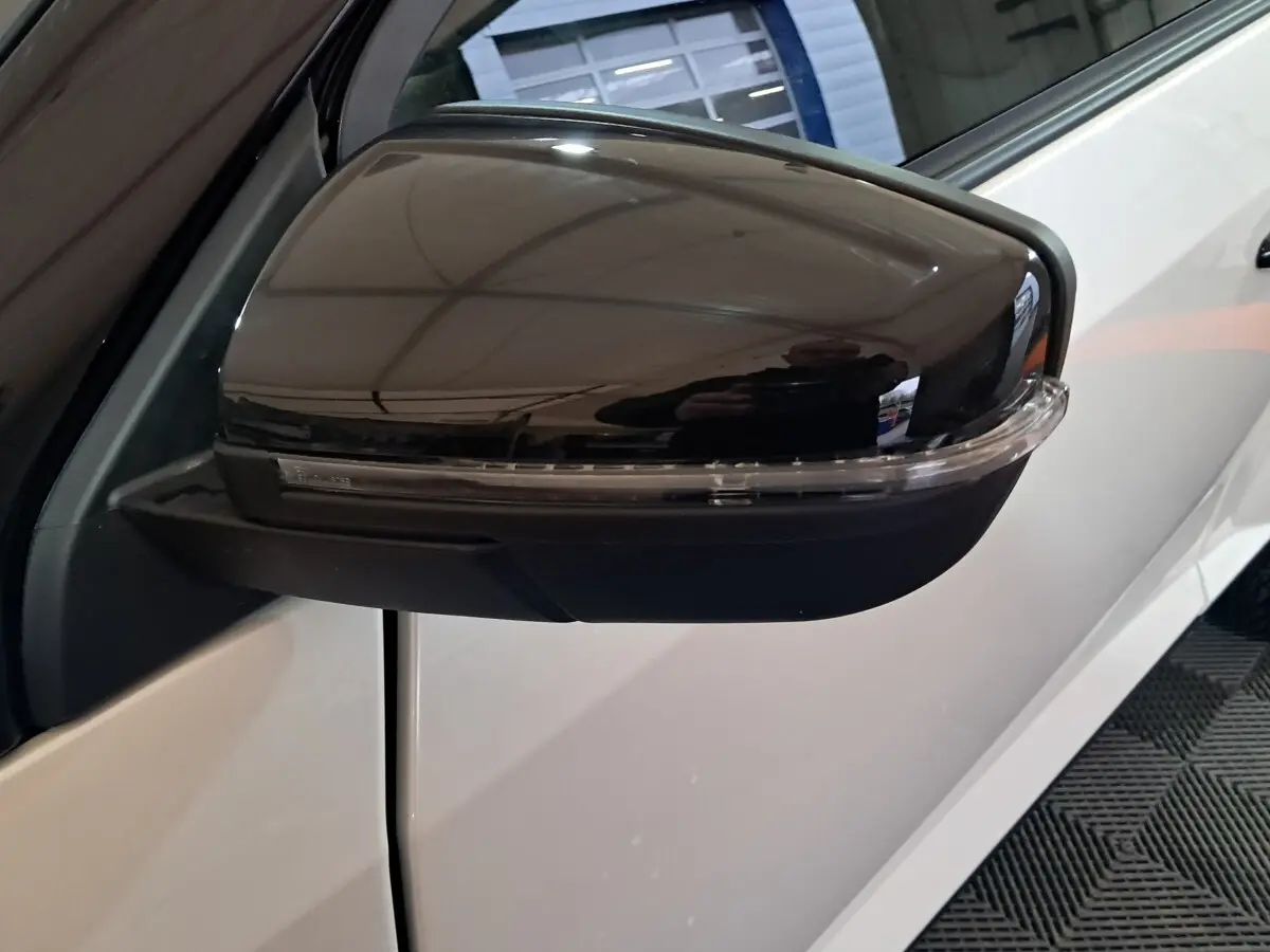 Gros plan sur le rétroviseur caméra côté gauche noir brillant d'une Aixam Ambition 0.5 City Coupe GTI blanche.