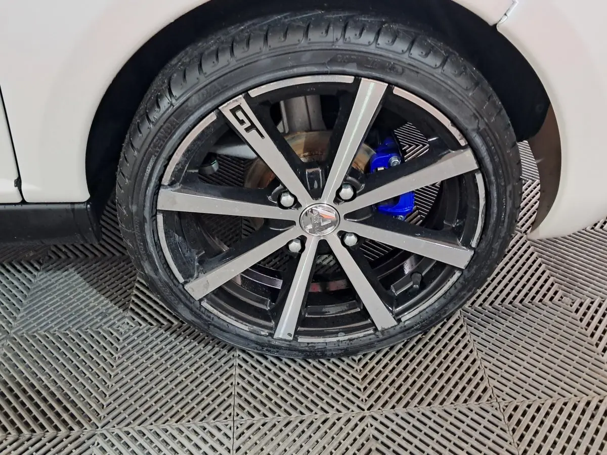 Gros plan sur la roue avant droite de l'AIXAM AMBITION 0.5 CITY COUPE GTI blanche avec étrier de frein bleu visible.