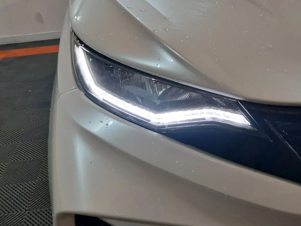 Gros plan sur le phare avant gauche blanc de l'AIXAM AMBITION 0.5 CITY COUPE GTI 2026 avec éclairage LED distinctif.