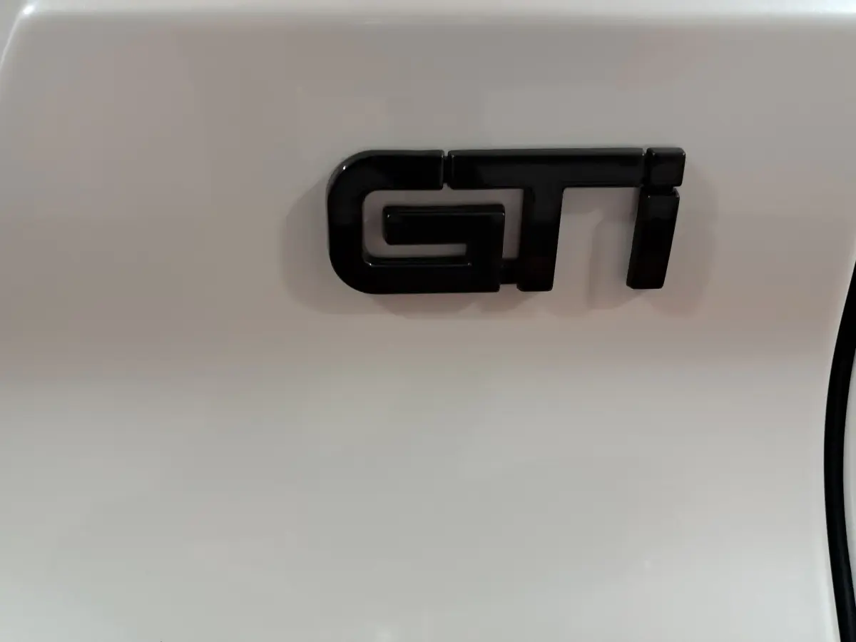 Gros plan sur l’inscription GTI noire sur la carrosserie blanche d’une Aixam Ambition 0.5 City Coupe 2026.