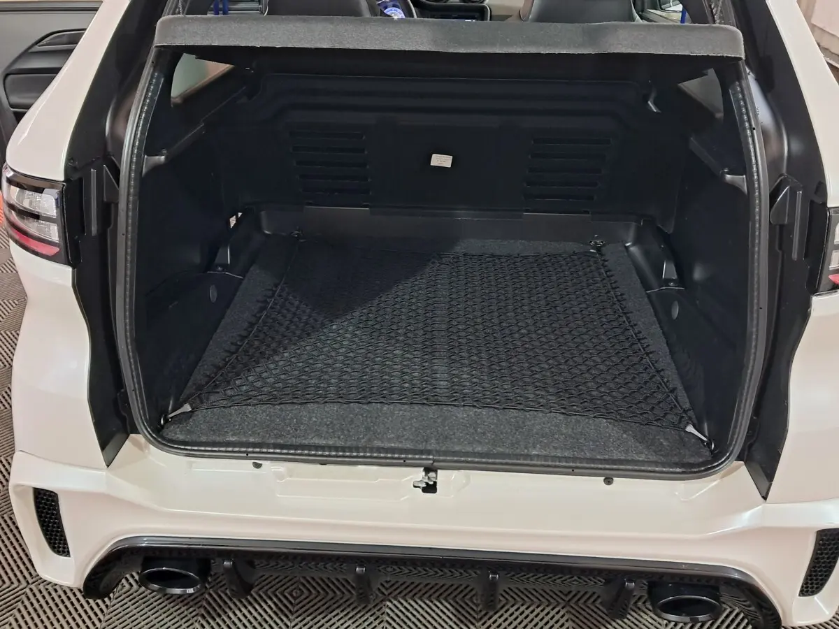 Vue arrière du coffre ouvert de l'AIXAM AMBITION 0.5 CITY COUPE GTI blanc, avec filet de rangement et détails noirs.