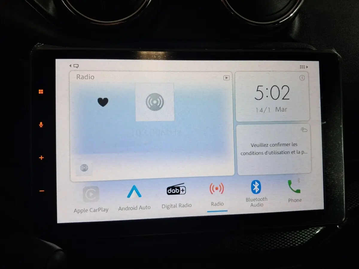 Écran tactile central de l'AIXAM AMBITION 0.5 CITY COUPE GTI blanc, affichant les options radio et connectivité.