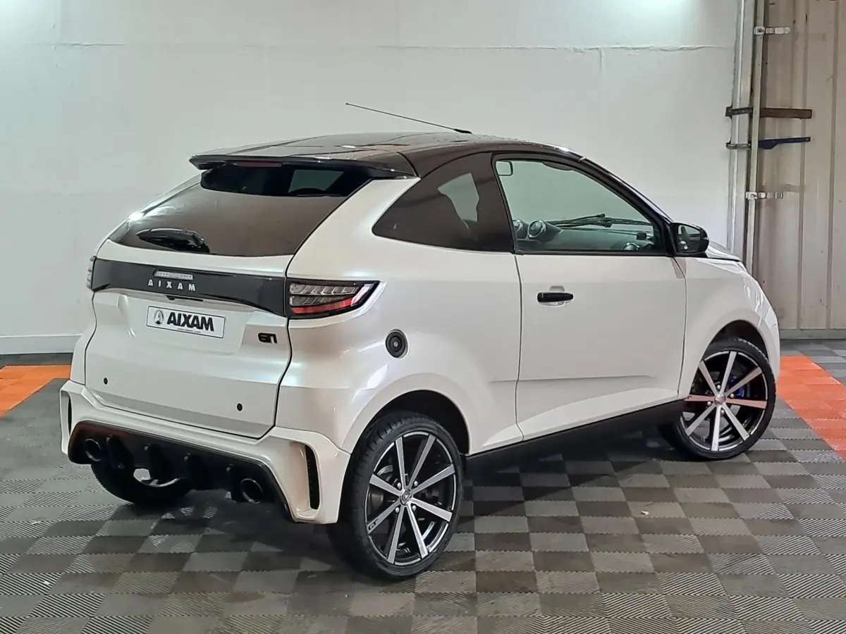Vue 3/4 arrière droite d'une AIXAM Ambition 0.5 City Coupe GTI blanche avec jantes noires et toit noir.