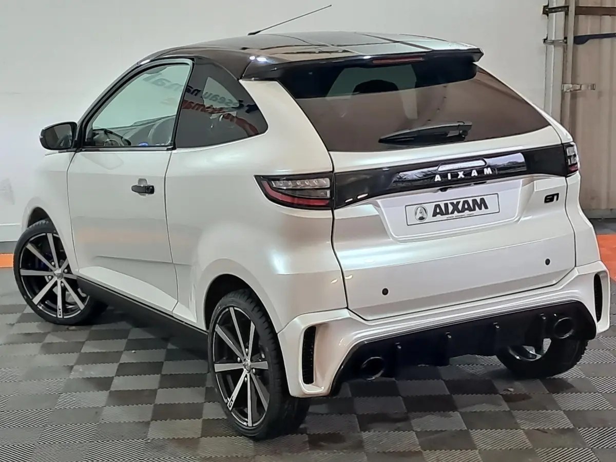 Vue 3/4 arrière gauche d'une AIXAM Ambition 0.5 City Coupe GTI blanche avec toit noir et jantes sport.