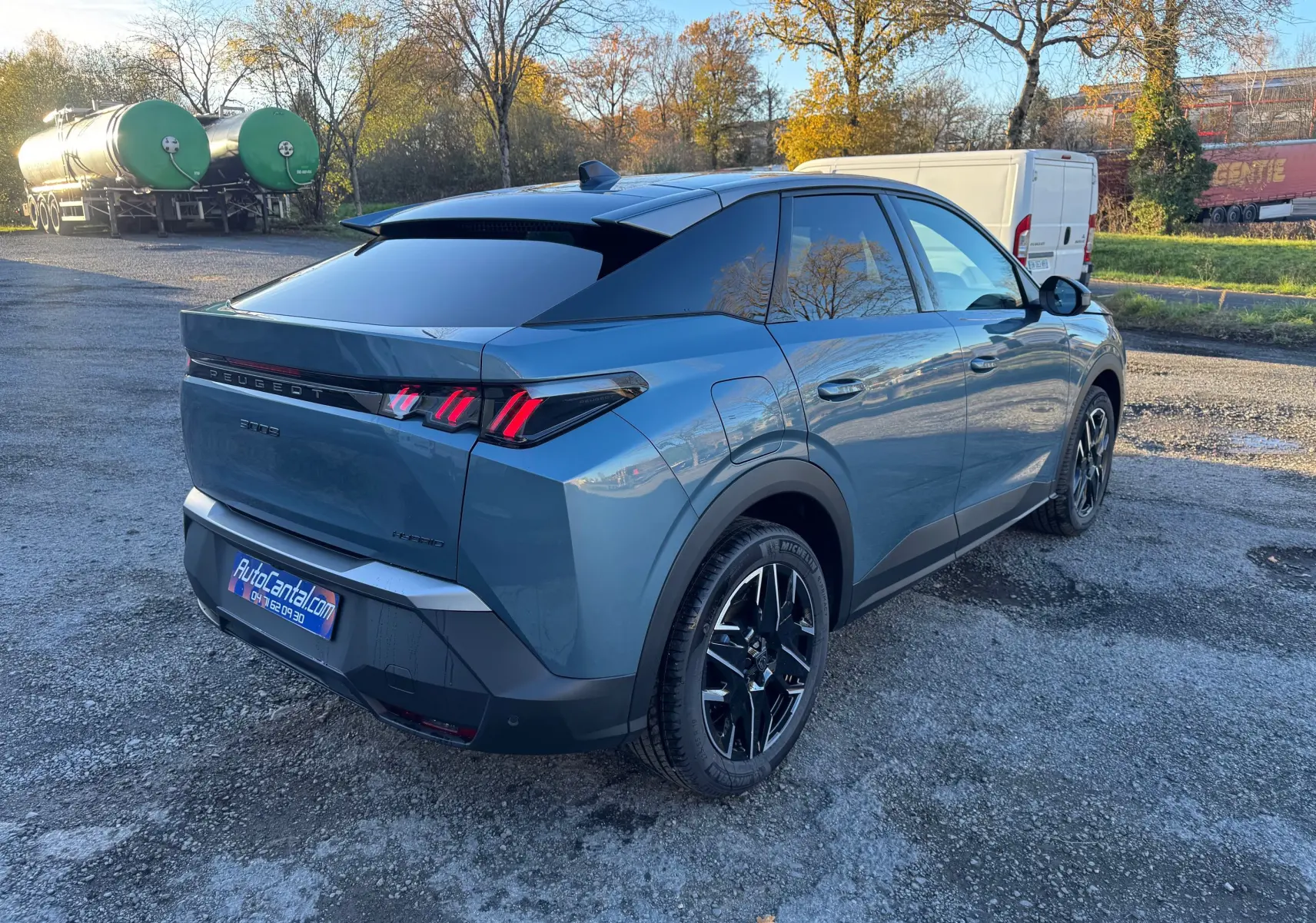 Vue 3/4 arrière droite d’un Peugeot 3008 Hybrid bleu Nogaro avec feux arrière à griffes et jantes noires brillantes.