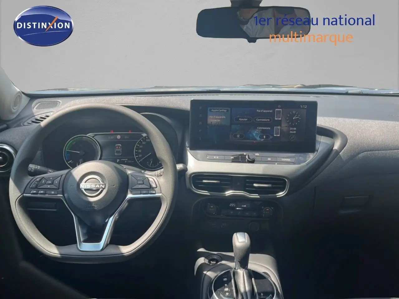 Vue intérieure frontale du tableau de bord du Nissan Juke Hybrid 2025 avec écran tactile et volant multifonction noir.