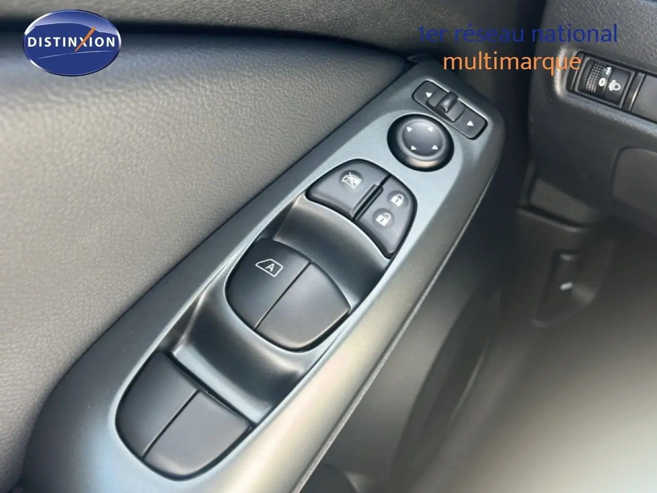 Gros plan sur les commandes de lève-vitres et rétroviseurs côté gauche intérieur d’un Nissan Juke gris Squale Metal 2025.