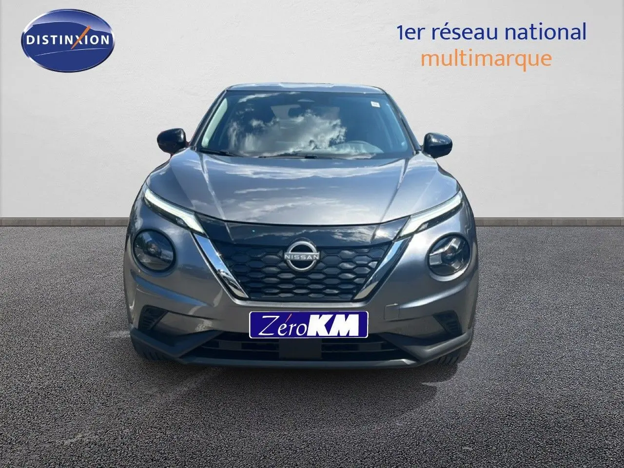 Vue frontale du Nissan Juke hybride gris squale métal avec calandre noire et phares ronds distinctifs.