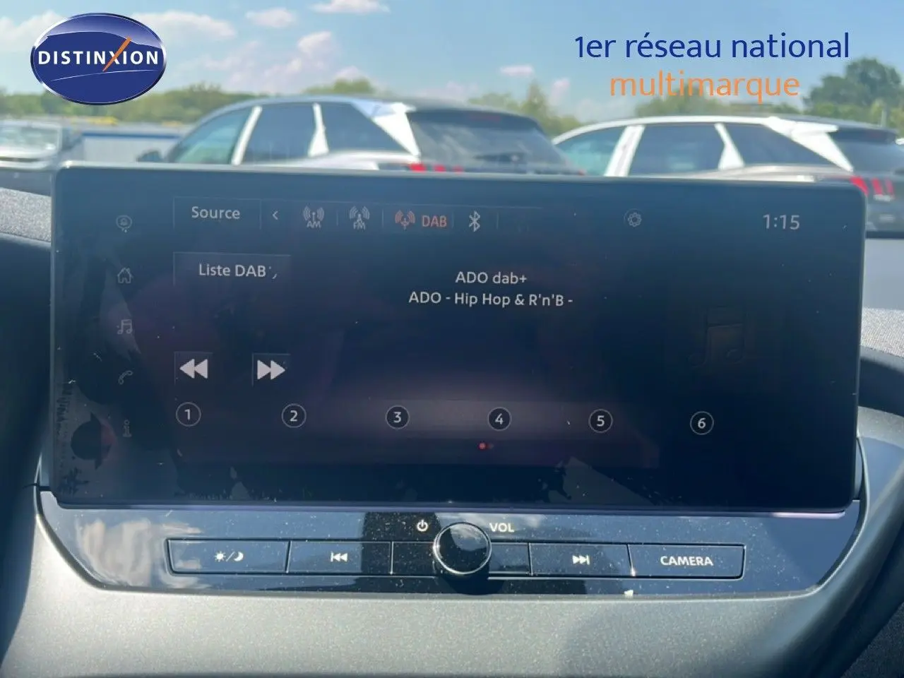 Écran tactile central du Nissan Juke hybride 2025 gris squale metal, affichant la radio DAB en extérieur lumineux.