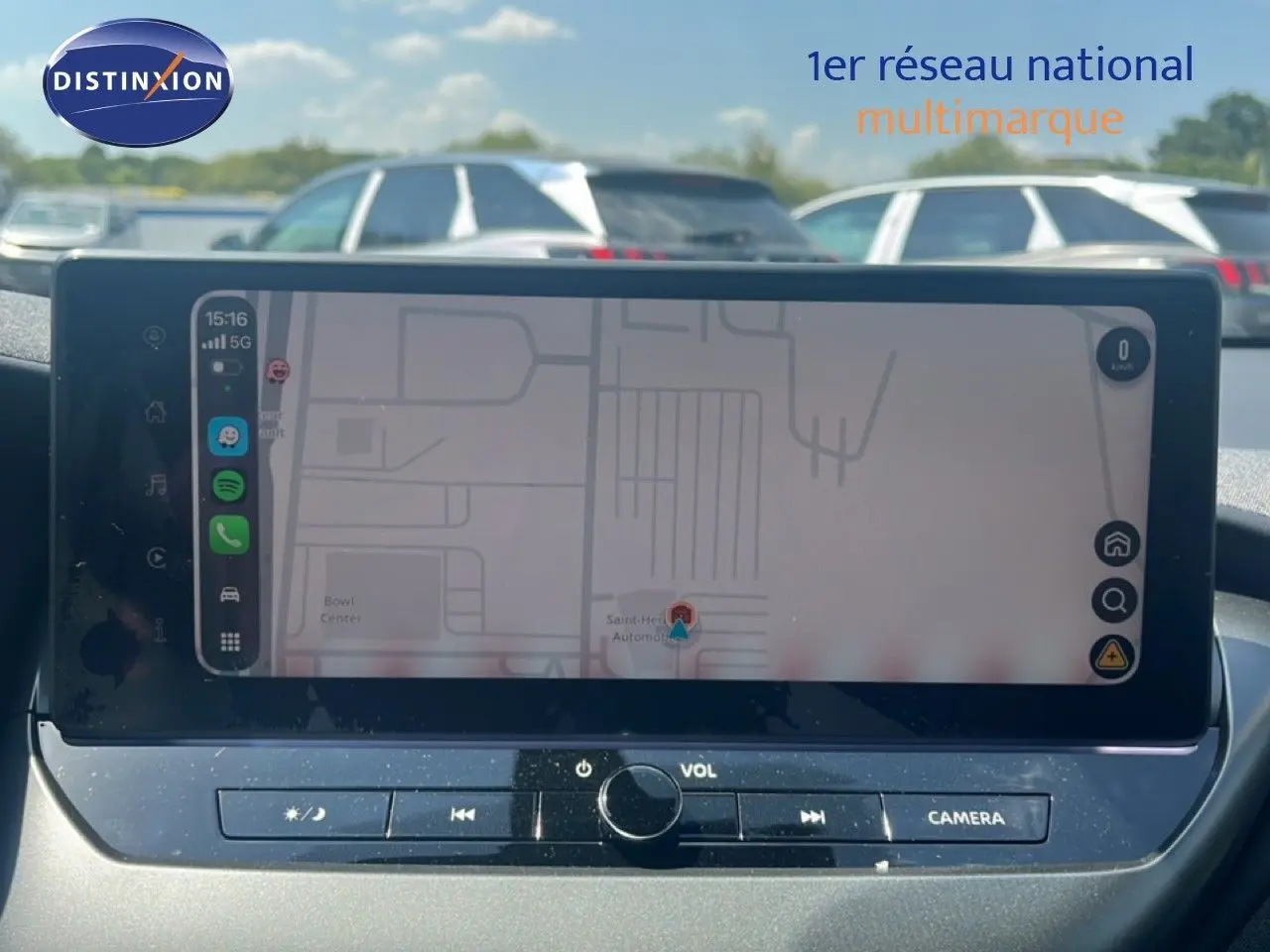 Vue intérieure du tableau de bord du Nissan Juke Hybrid 2025, écran tactile affichant la navigation, avec commandes audio en dessous.