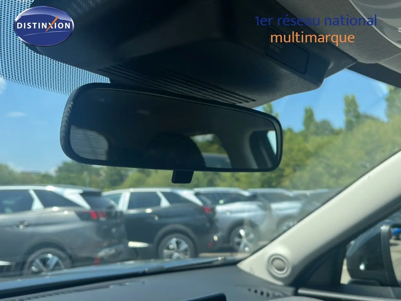 Vue intérieure du rétroviseur central d'un Nissan Juke gris, avec plusieurs SUV garés en arrière-plan.
