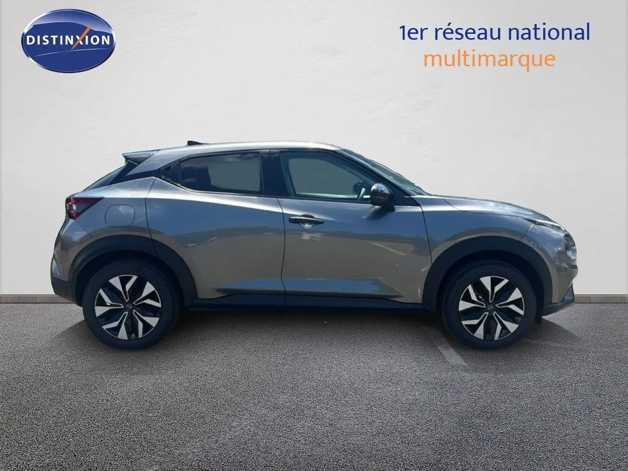 Vue de profil côté gauche d’un Nissan Juke Hybrid 2025 gris squale métal avec jantes distinctives noires et argentées.