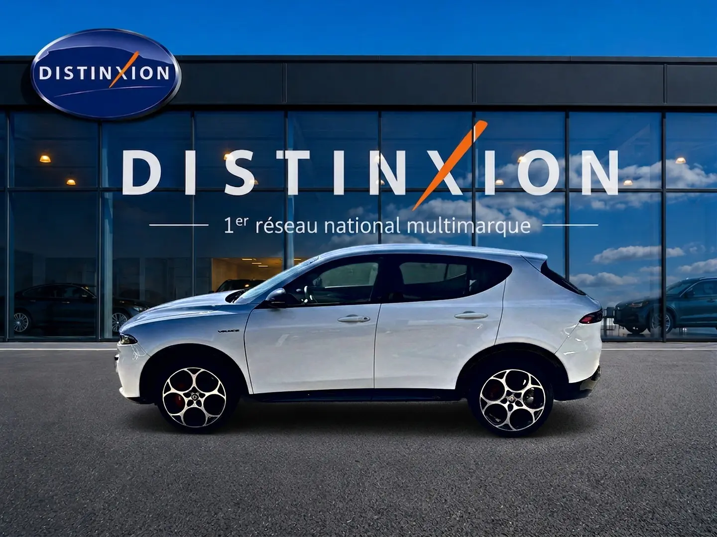 Vue de profil droit d'un Alfa Romeo Tonale blanc 2025 devant une vitrine Distinxion, avec jantes alu distinctives.