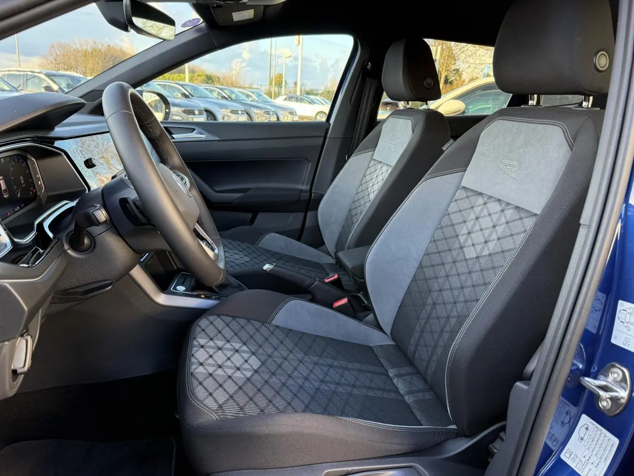 Intérieur côté conducteur du Volkswagen Taigo bleu récif, sièges R-Line en tissu et alcantara gris à motifs géométriques.
