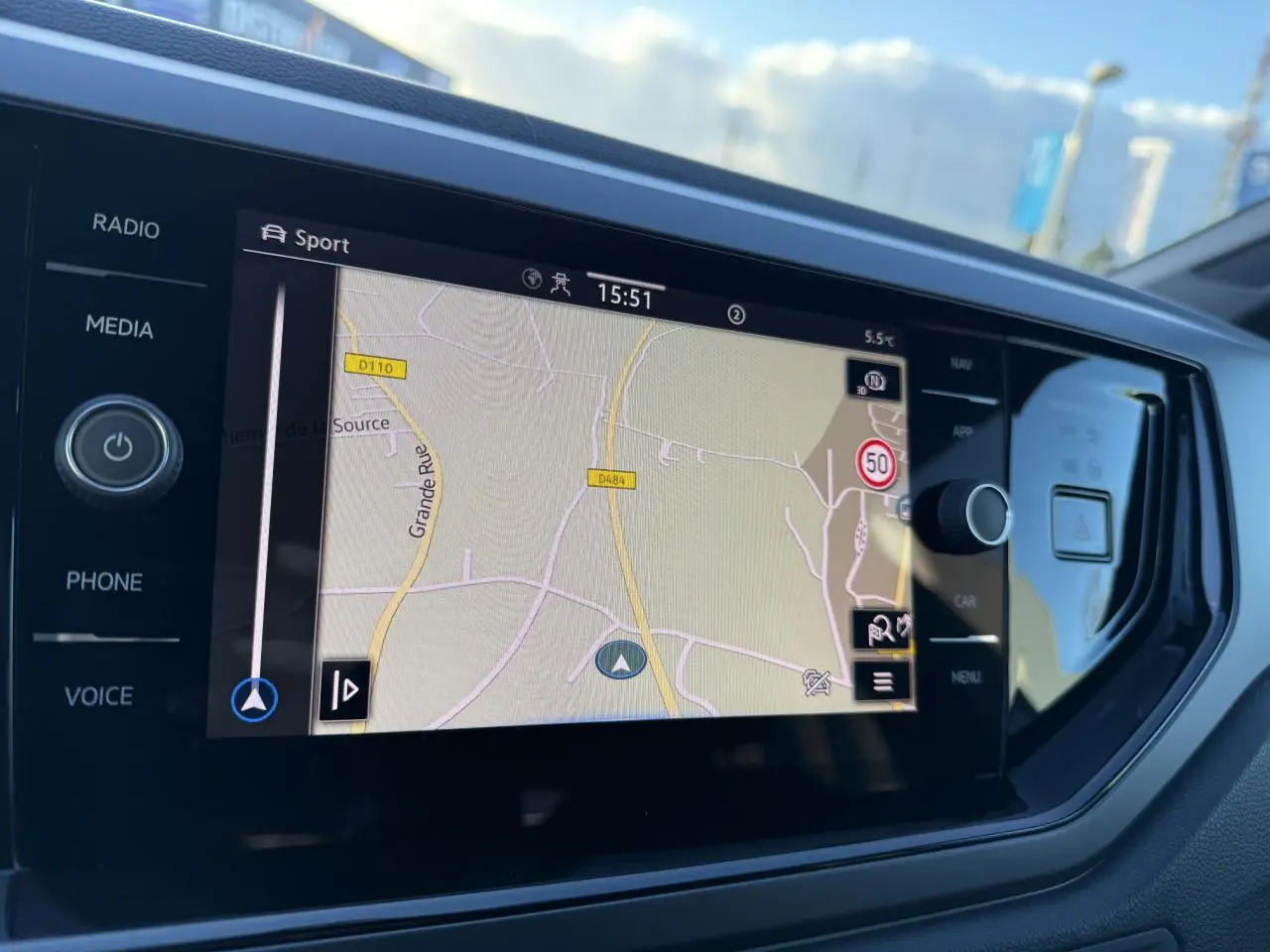 Écran tactile central du Volkswagen Taigo 2025 affichant la navigation avec commandes autour et reflet extérieur.