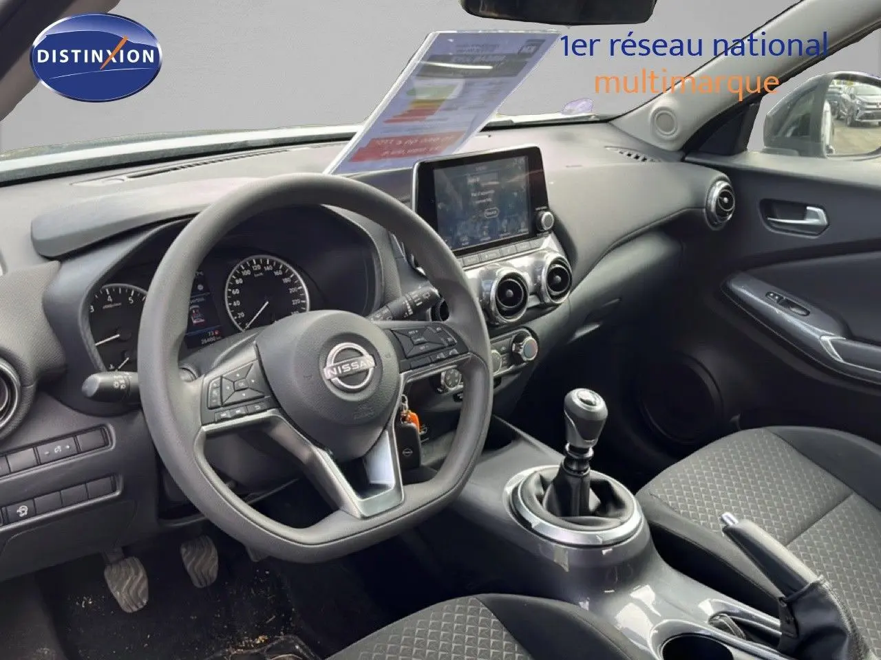 Vue intérieure côté conducteur du Nissan Juke noir métal 2023, mettant en valeur le volant multifonction et la console centrale moderne.