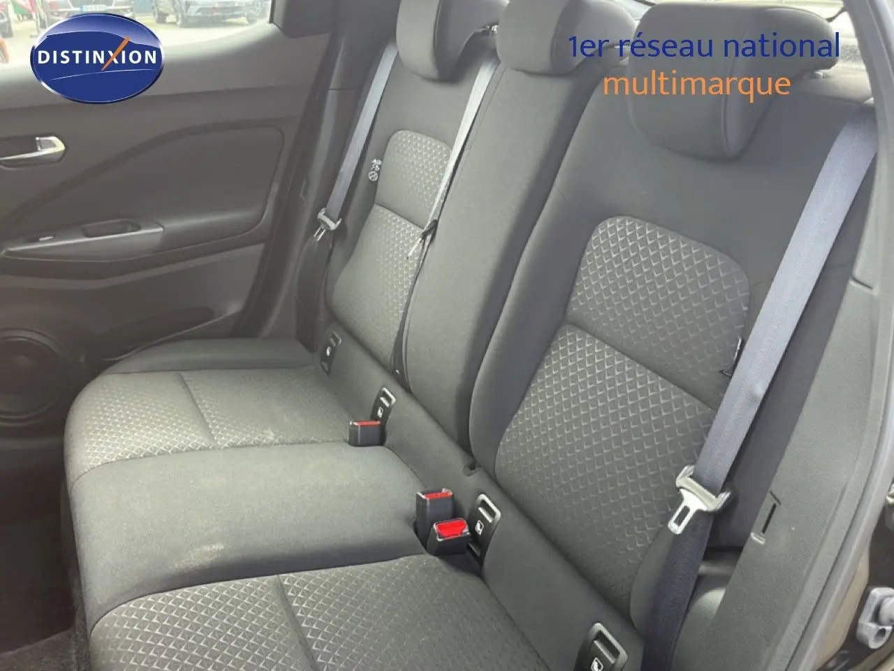 Vue intérieure côté droit des sièges arrière en tissu noir du Nissan Juke 2023, avec ceintures de sécurité visibles.