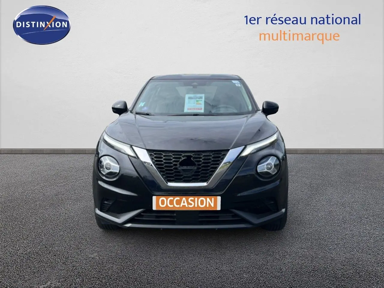 Vue frontale d'un Nissan Juke 2023 noir métal avec calandre en V chromée et phares ronds distinctifs.