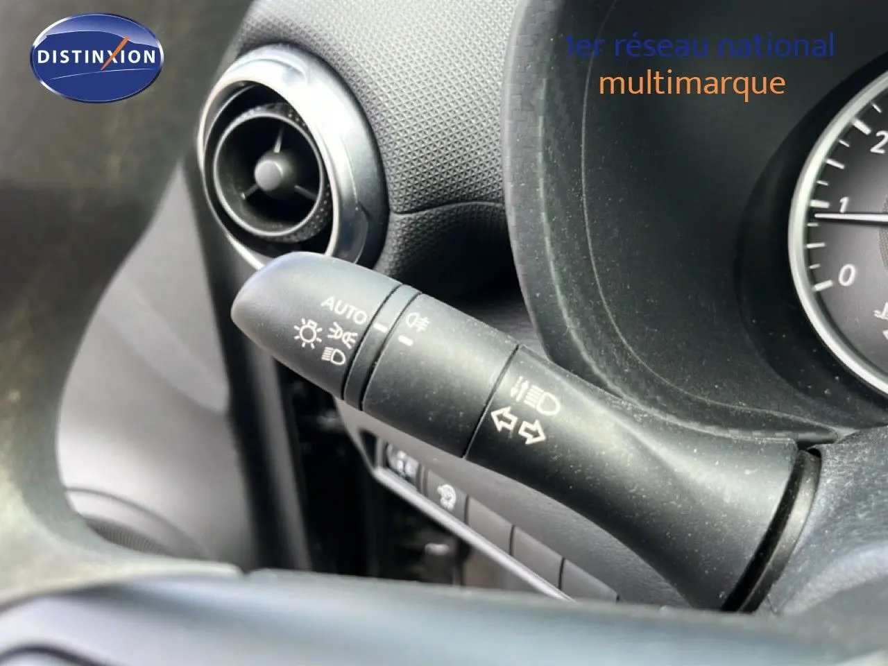 Gros plan sur la commande des phares et clignotants côté gauche du tableau de bord noir du Nissan Juke 2023.