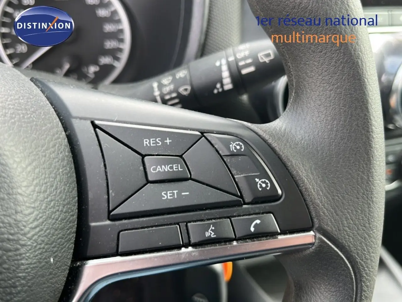 Gros plan sur les commandes au volant du Nissan Juke 2023 noir métal, mettant en valeur les boutons de régulateur de vitesse et téléphone.