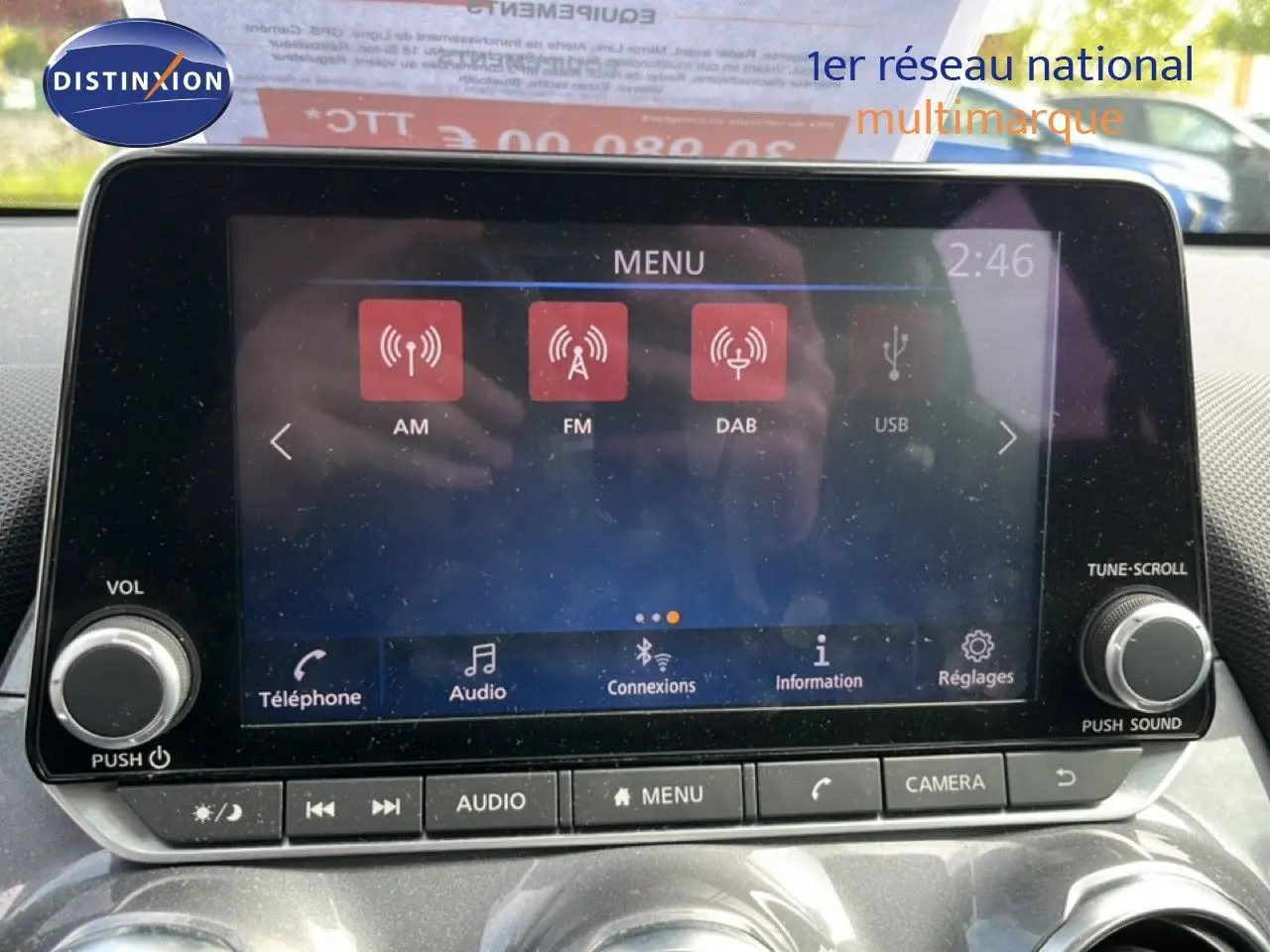Vue intérieure centrée sur l’écran tactile multimédia du Nissan Juke 2023, avec commandes audio et climatisation visibles.