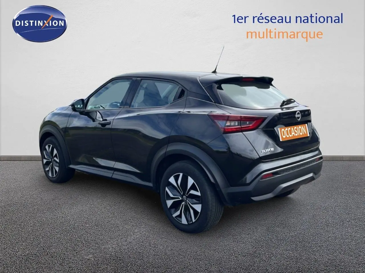Nissan Juke noir métal vu en 3/4 arrière côté gauche, soulignant ses lignes modernes et ses jantes stylisées.